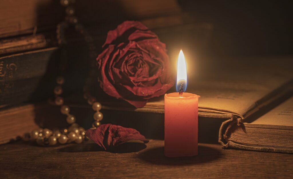 Idee regalo San Valentino: libri e accessori per chi ama leggere Foto: candela, rosa, libro, collaa di perle